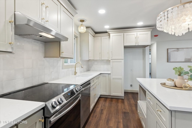 kitchen featuring dark wood-type flooring, sink, tasteful backsplash, decorative light fixtures, and stainless steel appliances