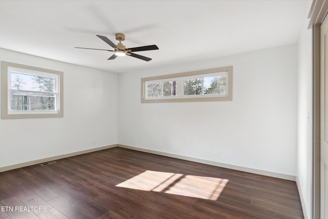 empty room featuring dark wood-type flooring, a wealth of natural light, and ceiling fan