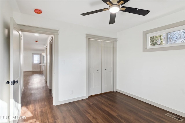 unfurnished bedroom with dark wood-type flooring, ceiling fan, and a closet