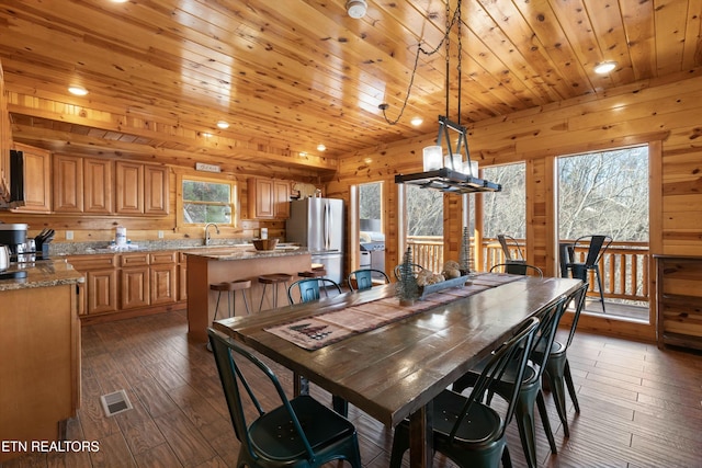 dining area with wood ceiling, a healthy amount of sunlight, dark hardwood / wood-style floors, and wood walls