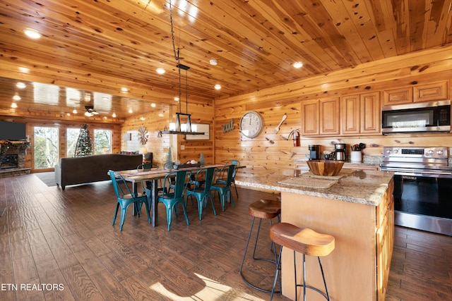 kitchen with dark wood-type flooring, appliances with stainless steel finishes, hanging light fixtures, light stone countertops, and wooden ceiling