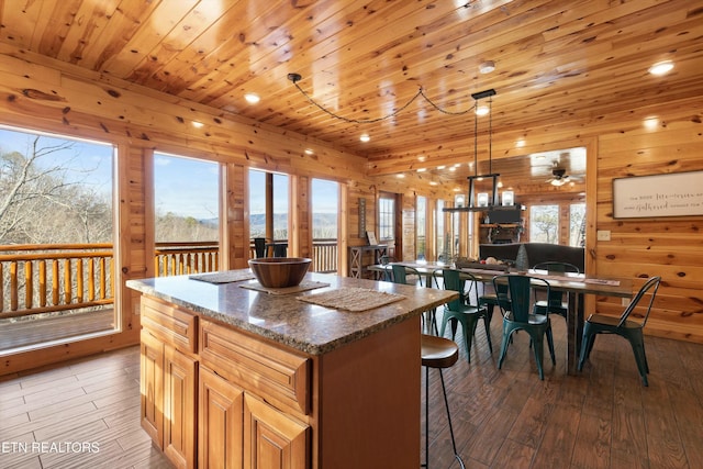 kitchen featuring stone countertops, a center island, hanging light fixtures, and wooden ceiling