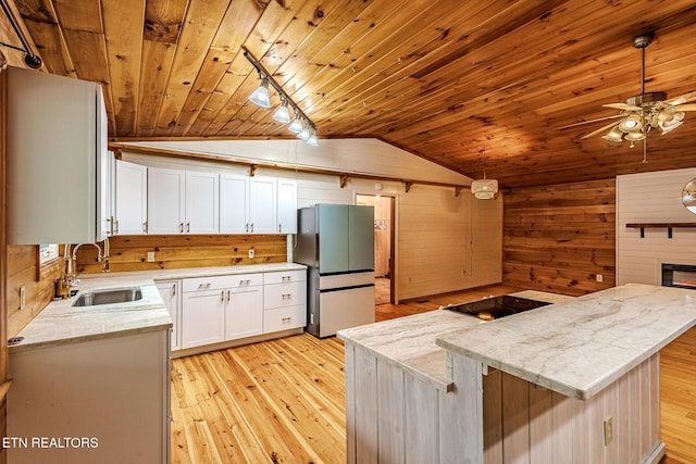 kitchen featuring sink, a center island, stainless steel refrigerator, pendant lighting, and white cabinets