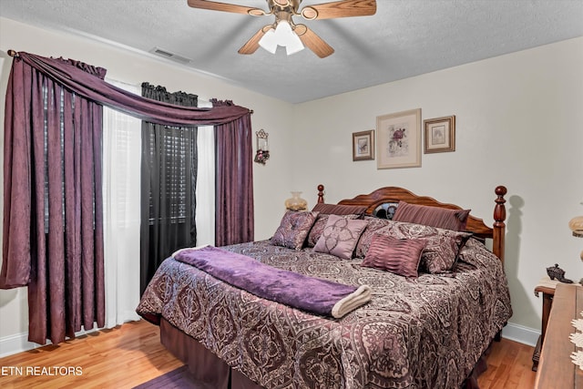 bedroom with ceiling fan, light hardwood / wood-style flooring, and a textured ceiling