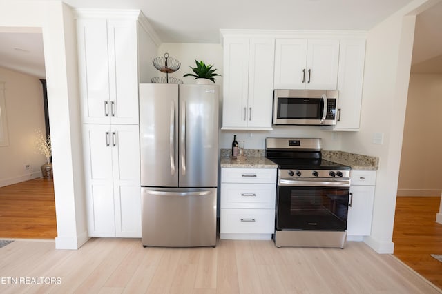 kitchen featuring stainless steel appliances, light stone countertops, white cabinets, and light hardwood / wood-style flooring