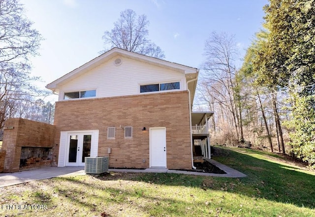 back of property with cooling unit, a balcony, a lawn, and french doors