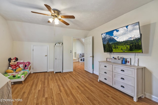 interior space featuring vaulted ceiling, a textured ceiling, ceiling fan, and light wood-type flooring