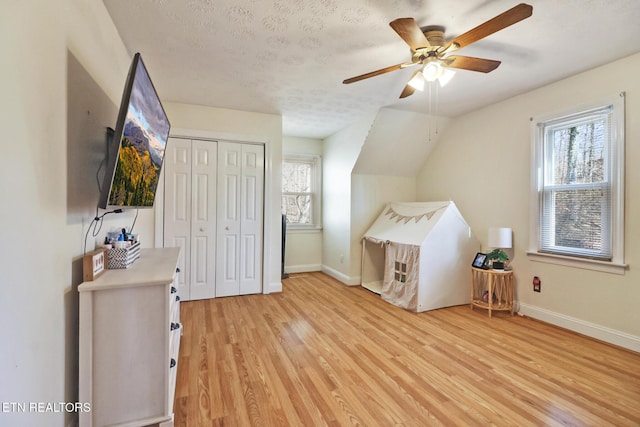 unfurnished bedroom featuring multiple windows, a textured ceiling, light wood-type flooring, and a closet