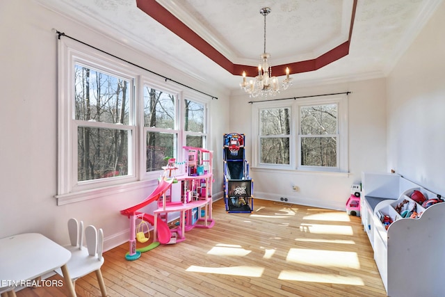 game room featuring crown molding, hardwood / wood-style floors, a chandelier, and a tray ceiling