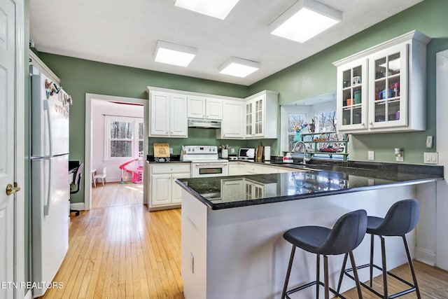 kitchen featuring white appliances, kitchen peninsula, and white cabinets