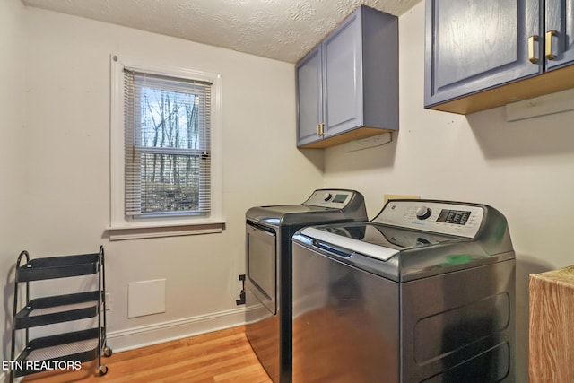 laundry area with washer and clothes dryer, light hardwood / wood-style flooring, cabinets, and a textured ceiling