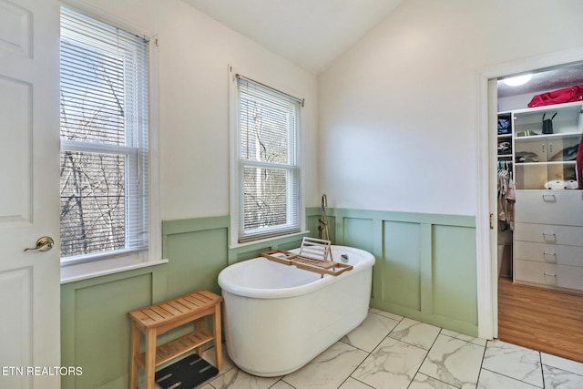 bathroom with a wealth of natural light, lofted ceiling, and a washtub