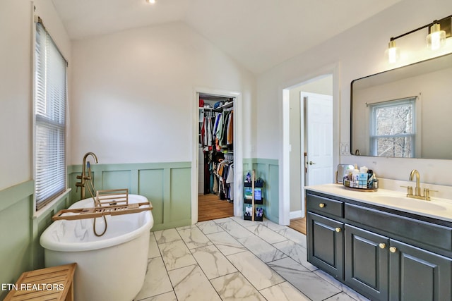 bathroom with a tub to relax in, vanity, and vaulted ceiling