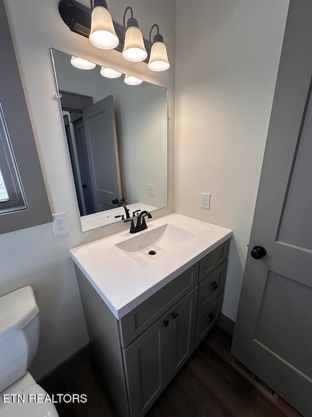 bathroom featuring vanity, toilet, and hardwood / wood-style floors