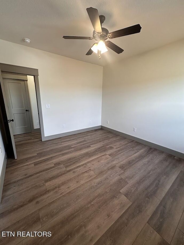 empty room with ceiling fan, dark hardwood / wood-style floors, and a textured ceiling