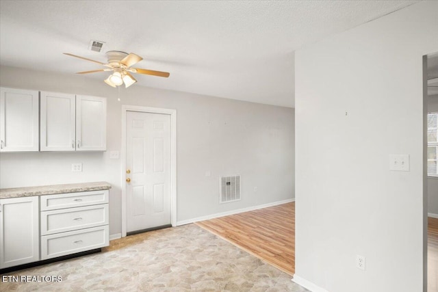 kitchen with ceiling fan, a textured ceiling, light hardwood / wood-style flooring, and white cabinets