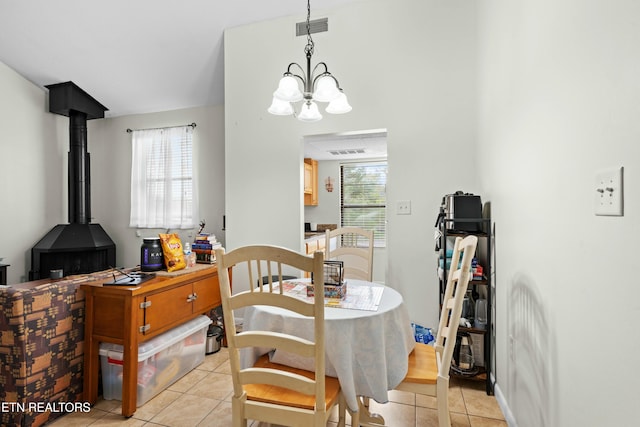 dining area featuring light tile patterned floors, a notable chandelier, and a wood stove