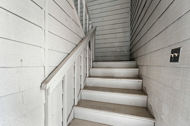 stairway featuring wood walls