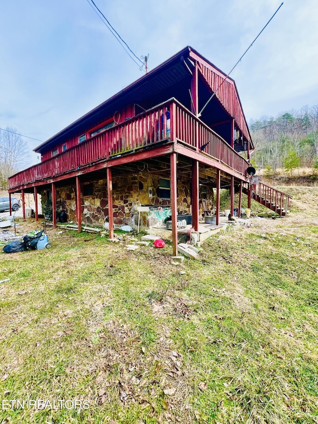 back of property featuring a wooden deck and a lawn