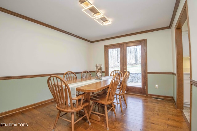 dining room with ornamental molding, light hardwood / wood-style floors, and french doors