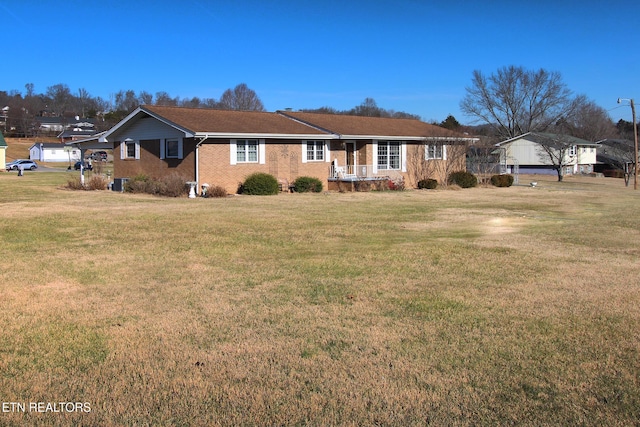 ranch-style house featuring brick siding, covered porch, and a front yard