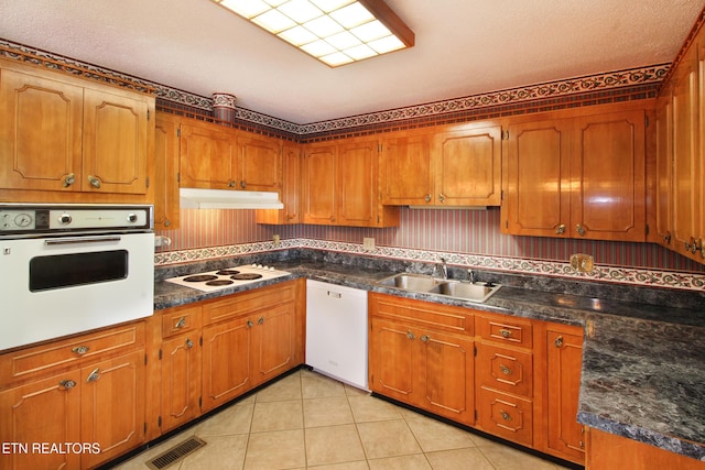 kitchen with light tile patterned floors, visible vents, a sink, white appliances, and under cabinet range hood