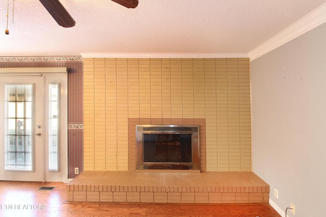 room details with a brick fireplace, visible vents, crown molding, and a textured ceiling