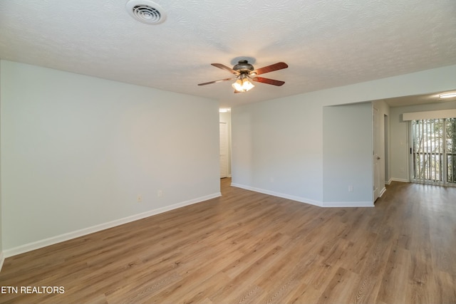 spare room with a textured ceiling and light wood-type flooring