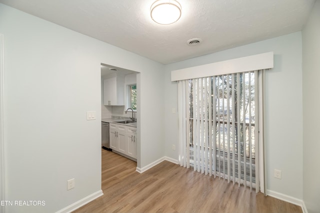 spare room featuring light hardwood / wood-style floors, sink, a textured ceiling, and a wealth of natural light