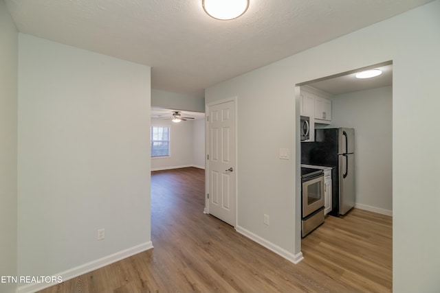 kitchen with white cabinetry, light hardwood / wood-style floors, ceiling fan, and appliances with stainless steel finishes