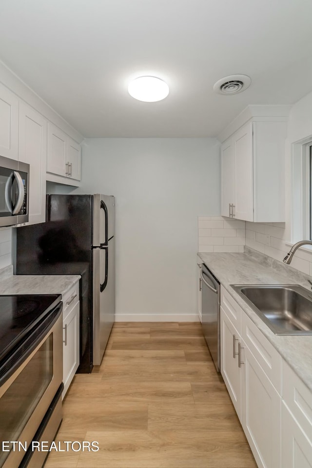 kitchen featuring stainless steel appliances, white cabinetry, and sink