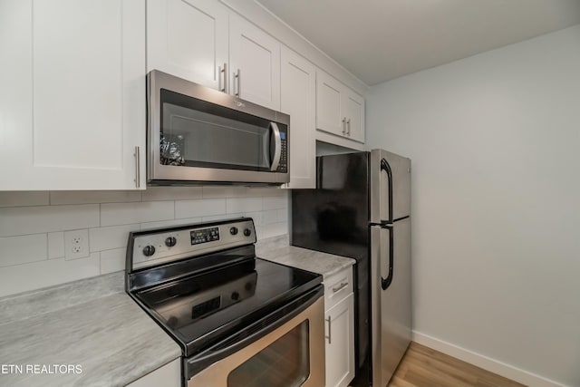 kitchen with white cabinetry, stainless steel appliances, light hardwood / wood-style floors, and decorative backsplash