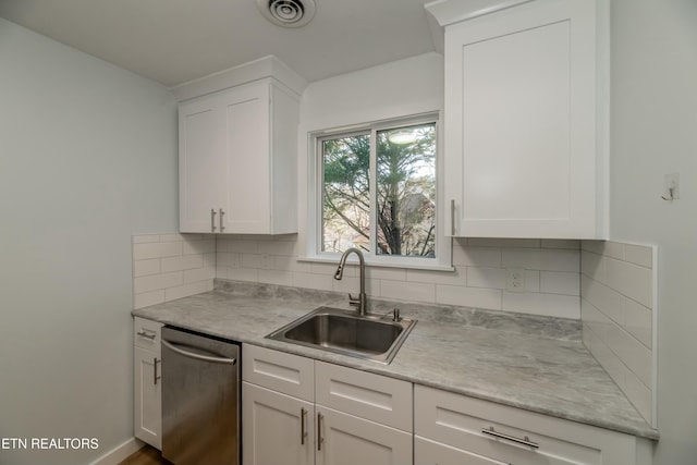 kitchen featuring stainless steel dishwasher, sink, decorative backsplash, and white cabinets