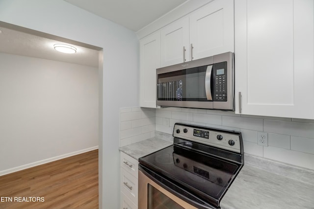 kitchen featuring white cabinetry, appliances with stainless steel finishes, light hardwood / wood-style flooring, and decorative backsplash