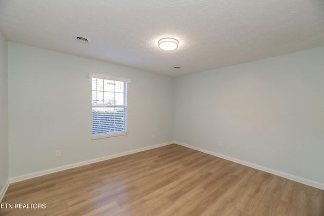 empty room featuring a textured ceiling and light wood-type flooring