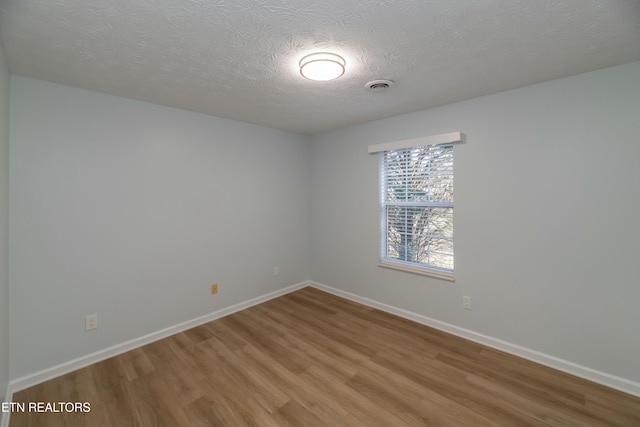 unfurnished room featuring hardwood / wood-style flooring and a textured ceiling