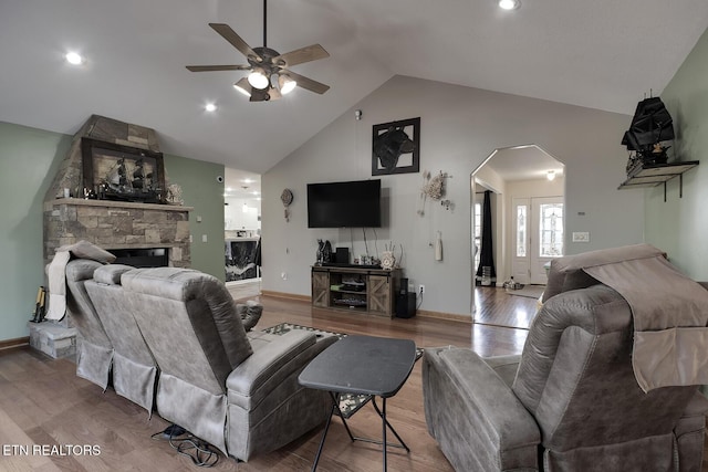 living room featuring ceiling fan, a stone fireplace, high vaulted ceiling, and light hardwood / wood-style flooring