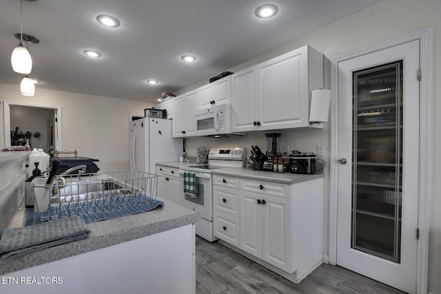 kitchen featuring white cabinetry, sink, white appliances, and decorative light fixtures