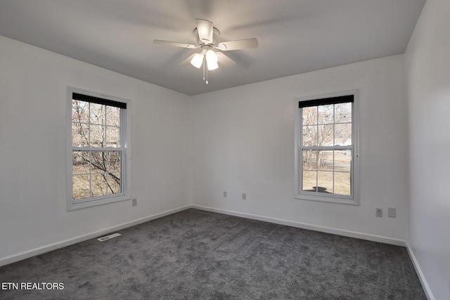 spare room with dark colored carpet and ceiling fan