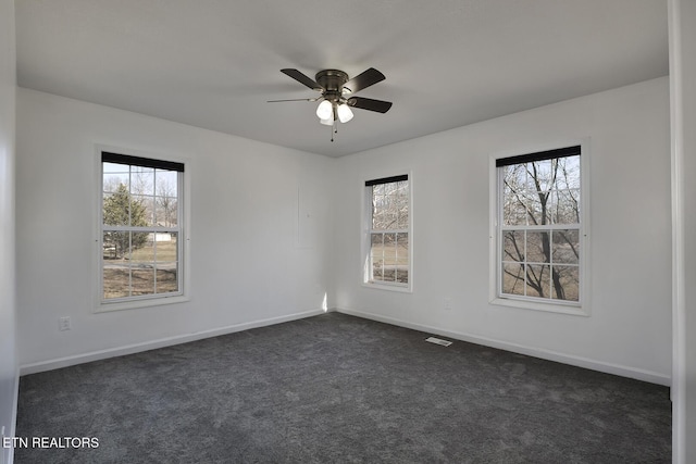 unfurnished room with ceiling fan and dark carpet