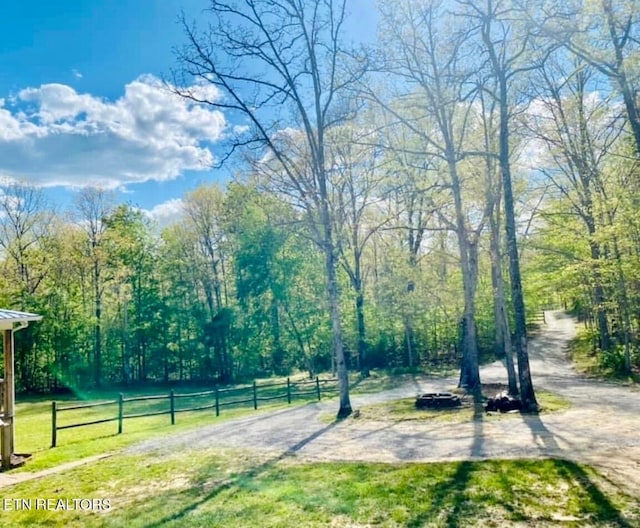 view of home's community featuring fence, a wooded view, and a lawn