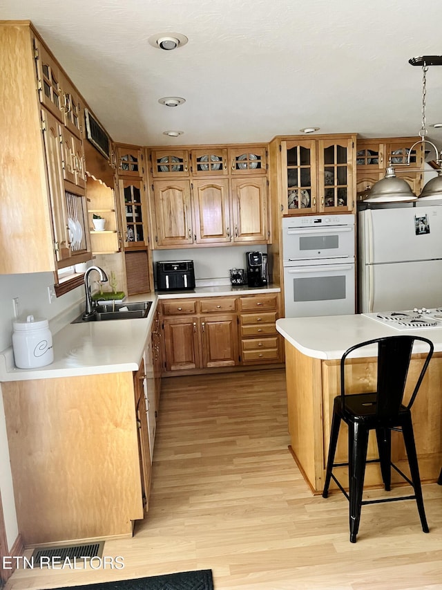 kitchen featuring white appliances, light countertops, a sink, and light wood-style flooring