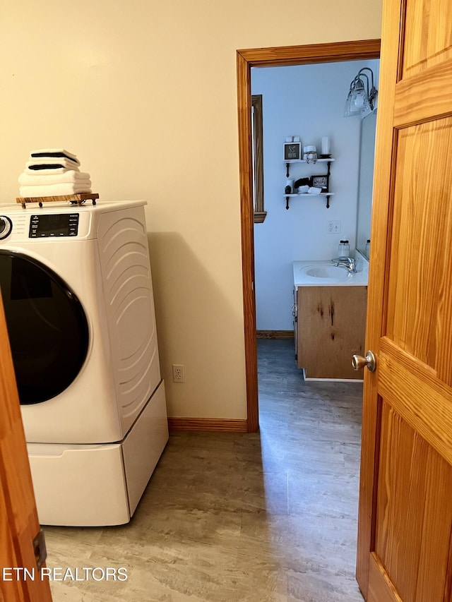 laundry room featuring laundry area, light wood-style floors, a sink, and washer / dryer