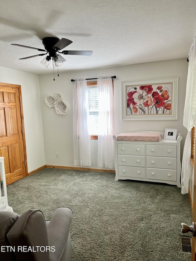 interior space featuring a textured ceiling, dark carpet, a ceiling fan, and baseboards