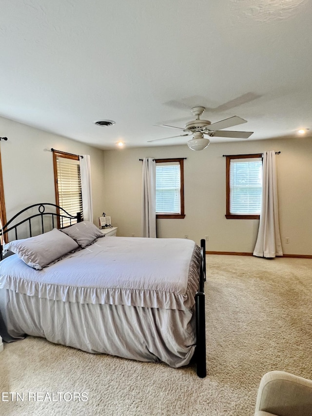 bedroom featuring light colored carpet, visible vents, baseboards, and multiple windows