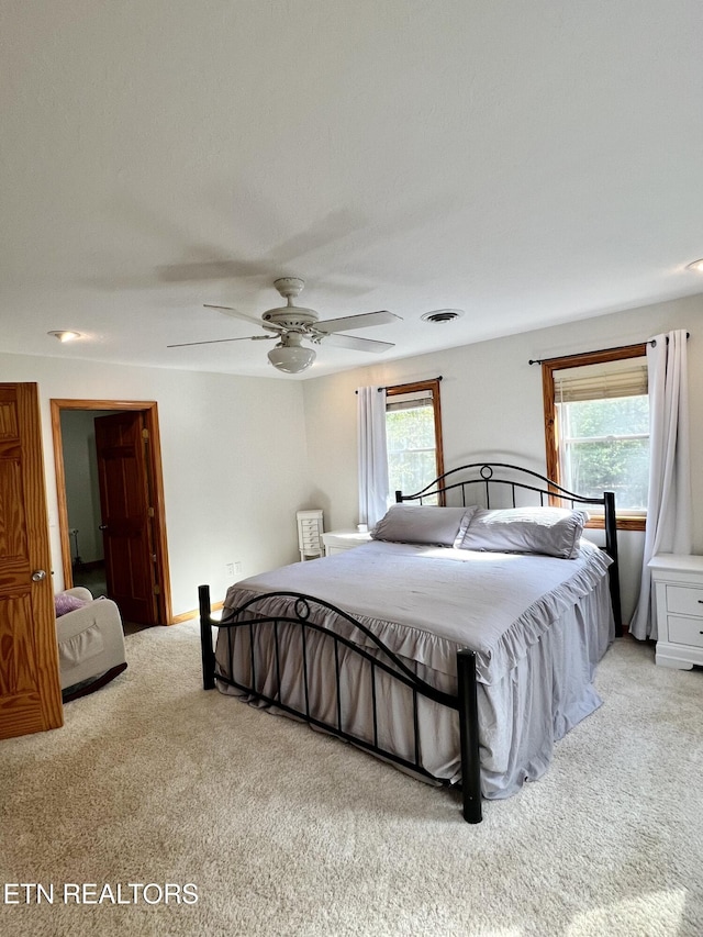 carpeted bedroom with multiple windows, visible vents, and a ceiling fan