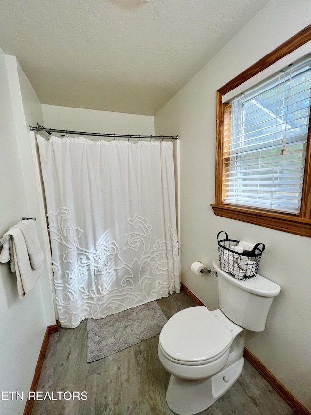 bathroom with toilet, baseboards, wood finished floors, and a shower with shower curtain