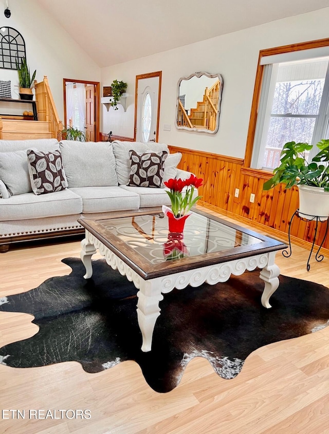 living area featuring a wainscoted wall, vaulted ceiling, wooden walls, and wood finished floors