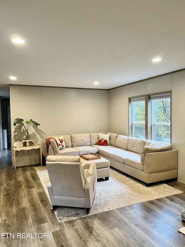 living area featuring a decorative wall, wood finished floors, and recessed lighting