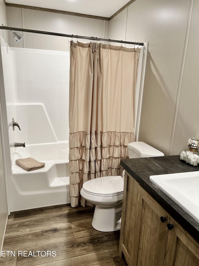 full bath with toilet, shower / bath combo, wood finished floors, and vanity